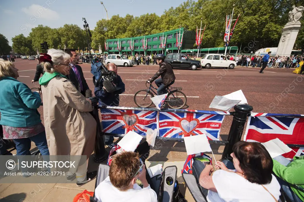England, London, Westminster. People sitting at the end of The Mall opposite Buckingham Palace in preparation for the Royal Wedding the following day.