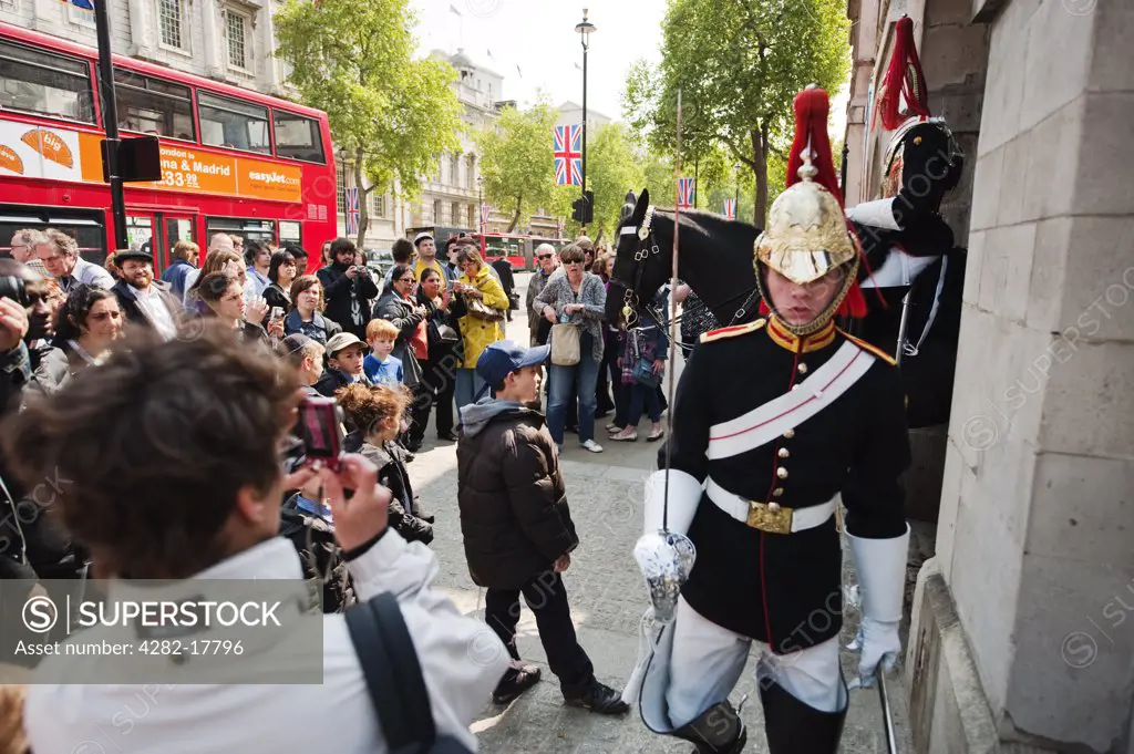 England, London, Whitehall. A large group of tourists watch and take photographs of Guards of the Blues and Royals on duty in Whitehall.