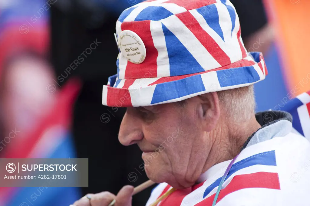 England, London, Westminster. An elderly Royal Wedding enthusiast wearing red,white and blue clothing, camped outside Westminster Abbey, two days before the big event in central London.