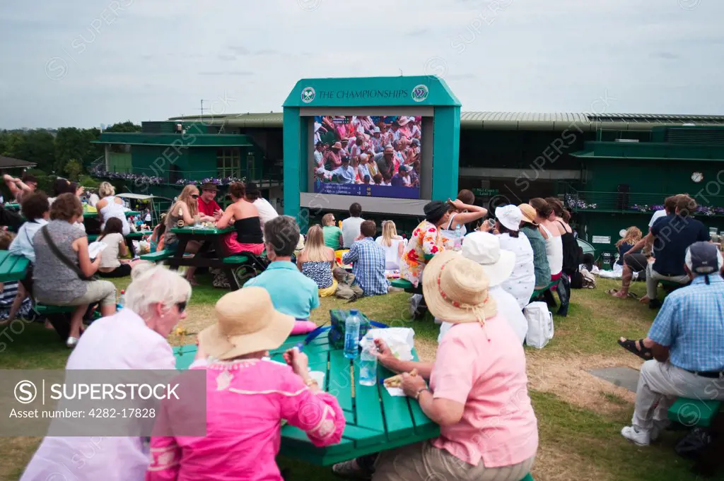 England, London, Wimbledon. Spectators watching the Wimbledon Lawn Tennis Championships 2010 on a giant TV screen from Henman Hill.