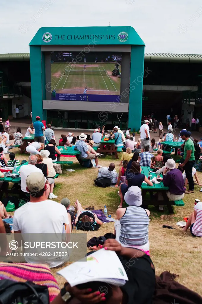 England, London, Wimbledon. Spectators watching the Wimbledon Lawn Tennis Championships 2010 on a giant TV screen from Henman Hill.