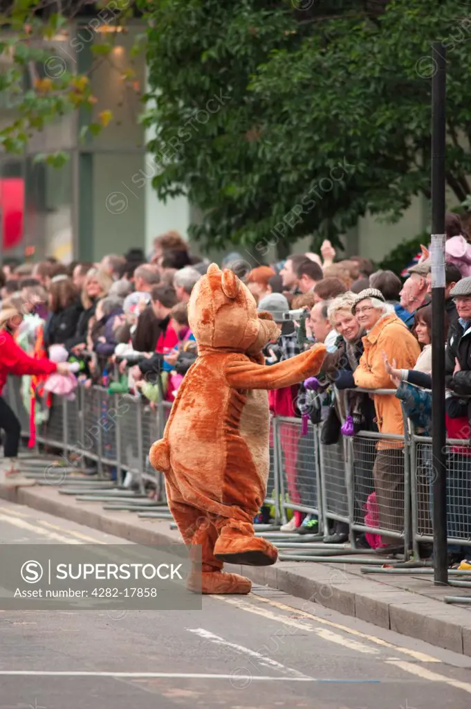 England, London, City of London. Mr Bear from Gensler's float greeting spectators lining the procession route of the annual Lord Mayor's Show in the City of London.
