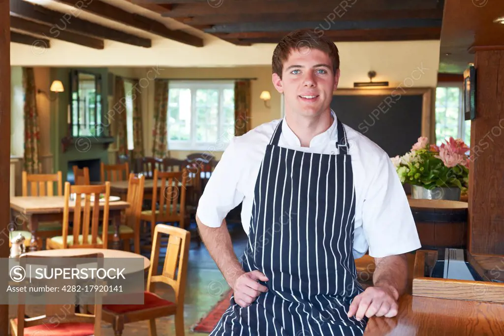 Chef Wearing Whites And Apron Sitting In Restaurant
