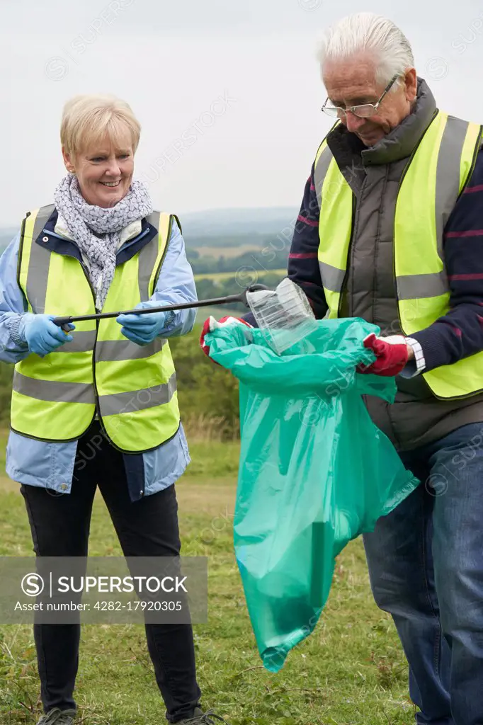 Helpful Senior Couple Collecting Litter In Countryside   