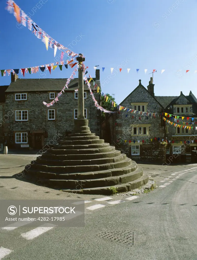 England, Derbyshire, Bonsall. The Market Cross and King's Head pub decorated with bunting for the village well dressings in August.