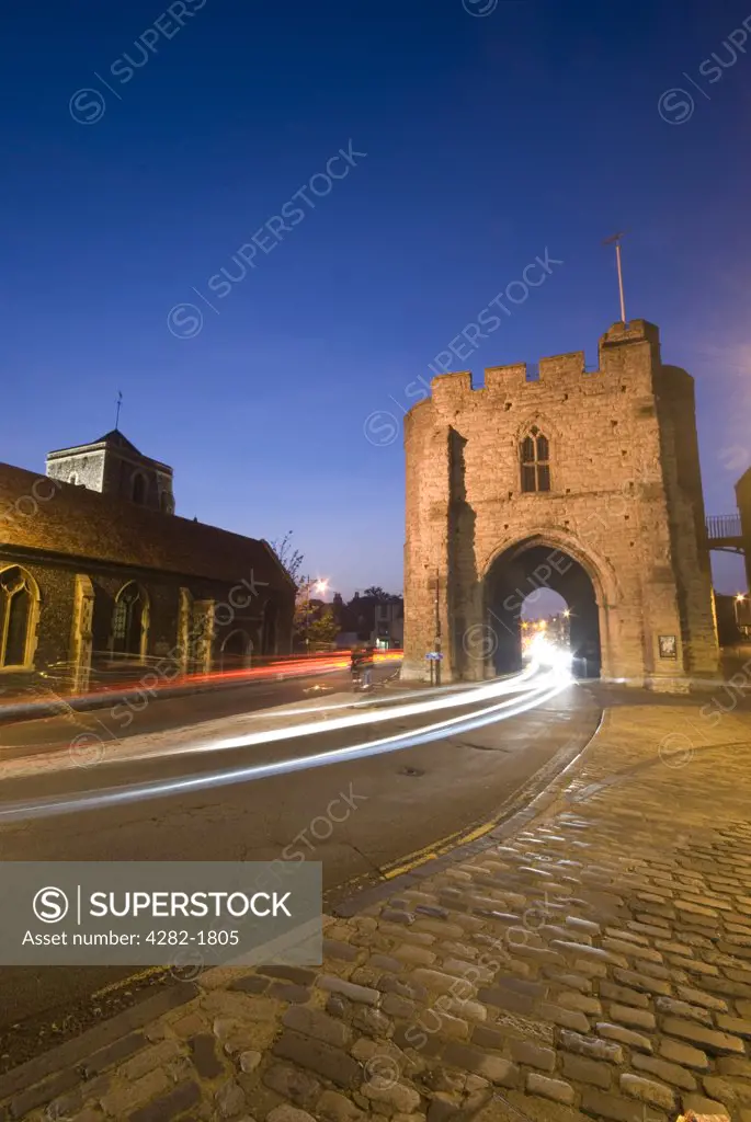 England, Kent, Canterbury. The Westgate Tower in Canterbury lit up at night with trials of light from passing traffic.