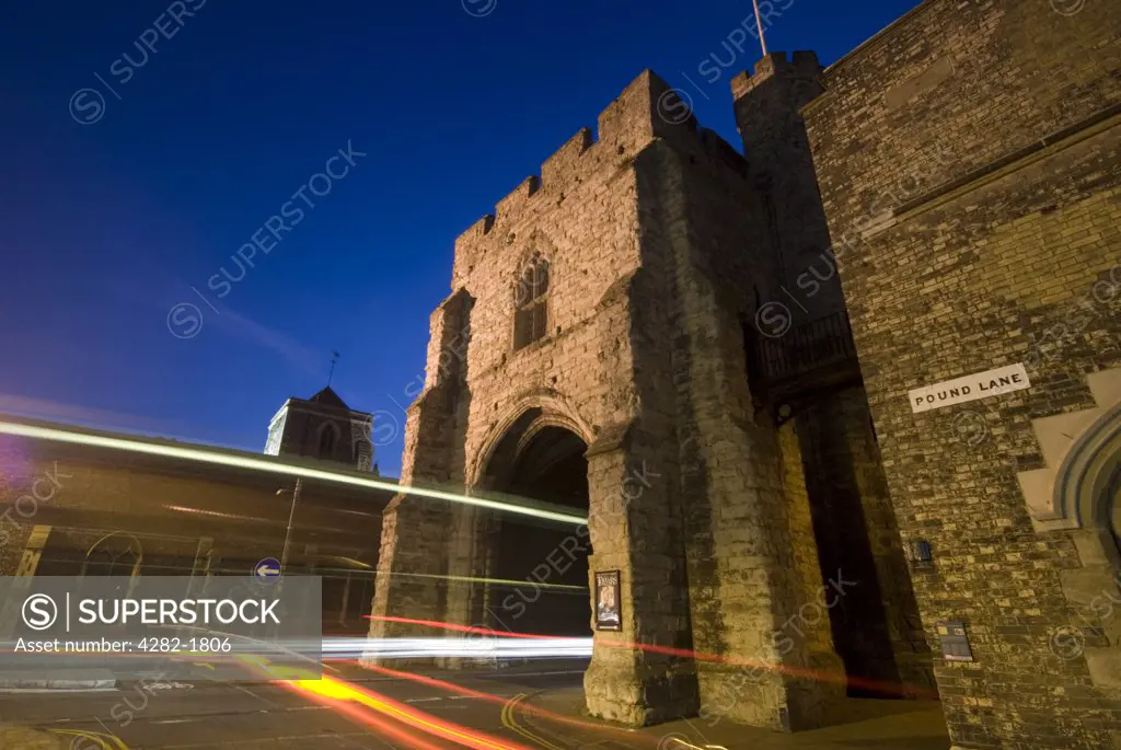 England, Kent, Canterbury. The Westgate Tower in Canterbury lit up at night with trials of light from passing traffic.