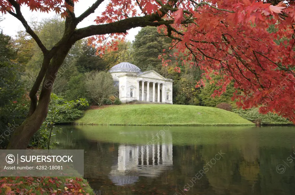 England, Wiltshire, Warminster. The Pantheon designed by Henry Filtcroft viewed across the lake through red Japenese Maple leaves at Stourhead gardens in autumn.