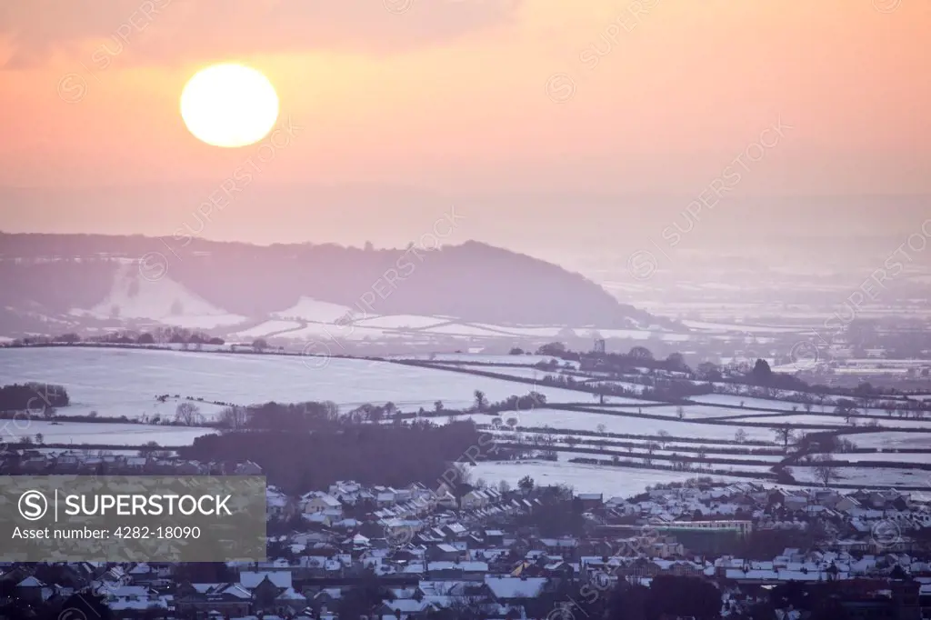 England, Somerset, Glastonbury. View over Glastonbury town covered in snow, from the top of the Tor at sunset.