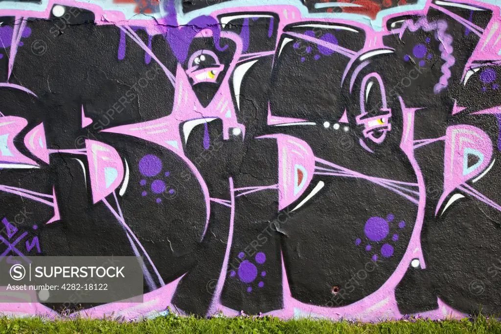 England, Devon, Plymouth. Bright coloured graffiti on a wall in a public park.