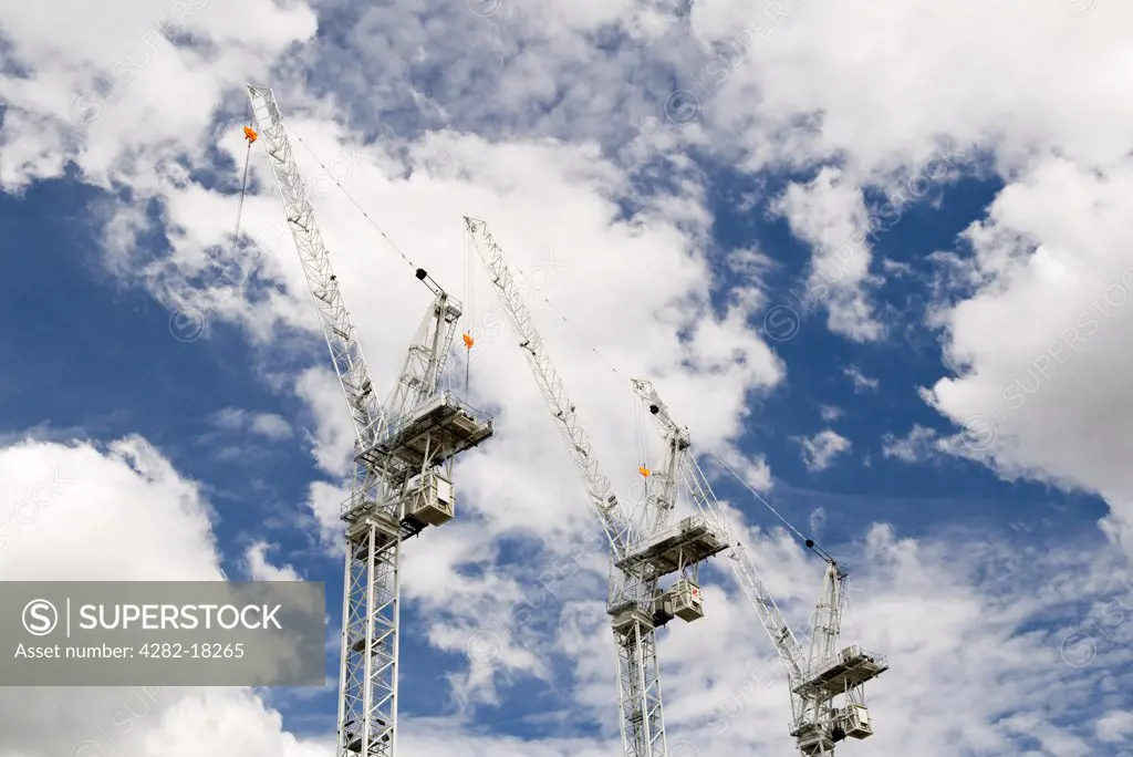 England, London, Southwark. Looking up to three cranes against a cloudy sky in London.