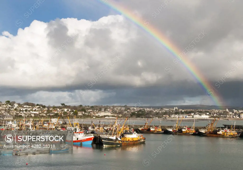 England, Cornwall, Newlyn. A rainbow over fishing boats moored in Newlyn harbour.