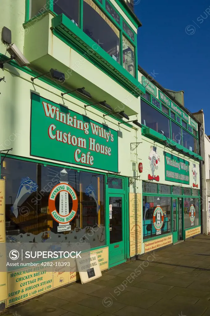 England, North Yorkshire, Scarborough. 'Winking Willy's Custom House Cafe' and 'Famous Fish and Chip Shop' restaurants on the seafront at Scarborough.