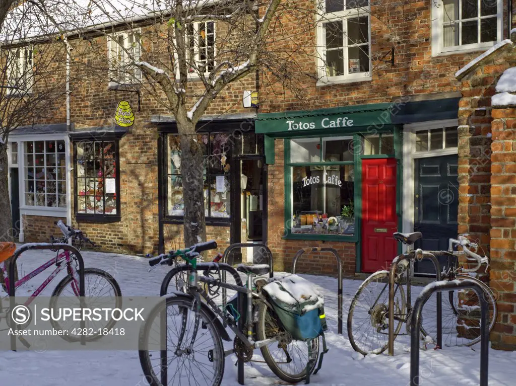 England, North Yorkshire, York. Bicycles locked to bike racks in the snow outside a row of shops in Minster Close.