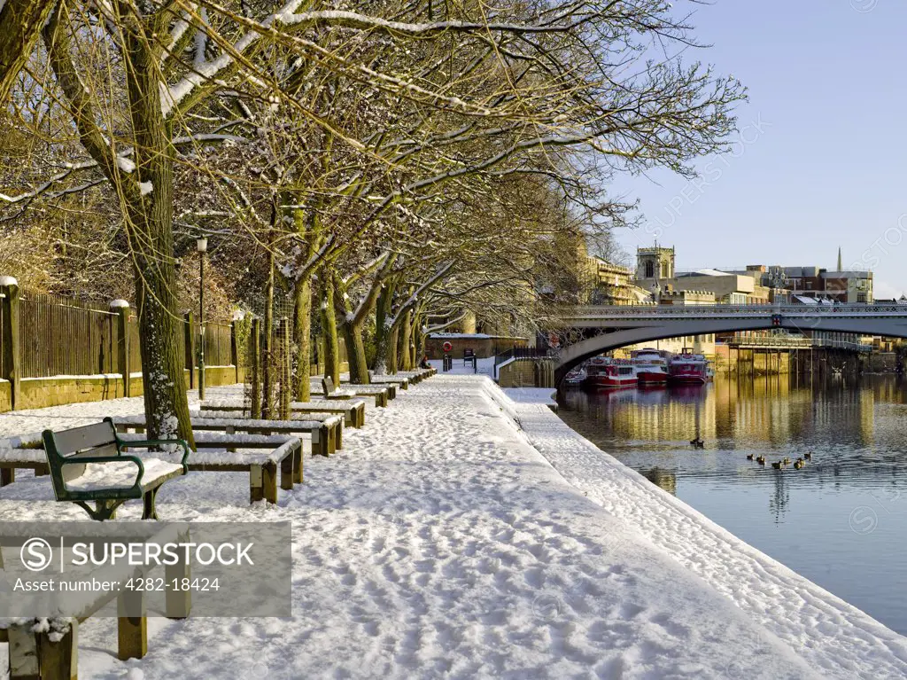 England, North Yorkshire, York. Riverside walk covered in snow along the River Ouse looking towards Lendal Bridge.