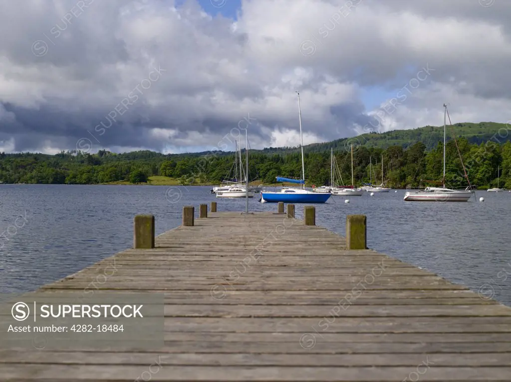 England, Cumbria, Ambleside. View along a wooden jetty towards boats moored on Lake Windermere at Waterhead.
