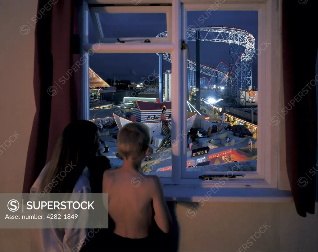 England, Lancashire, Blackpool. Children standing at a window looking at  the fun fair in Blackpool.