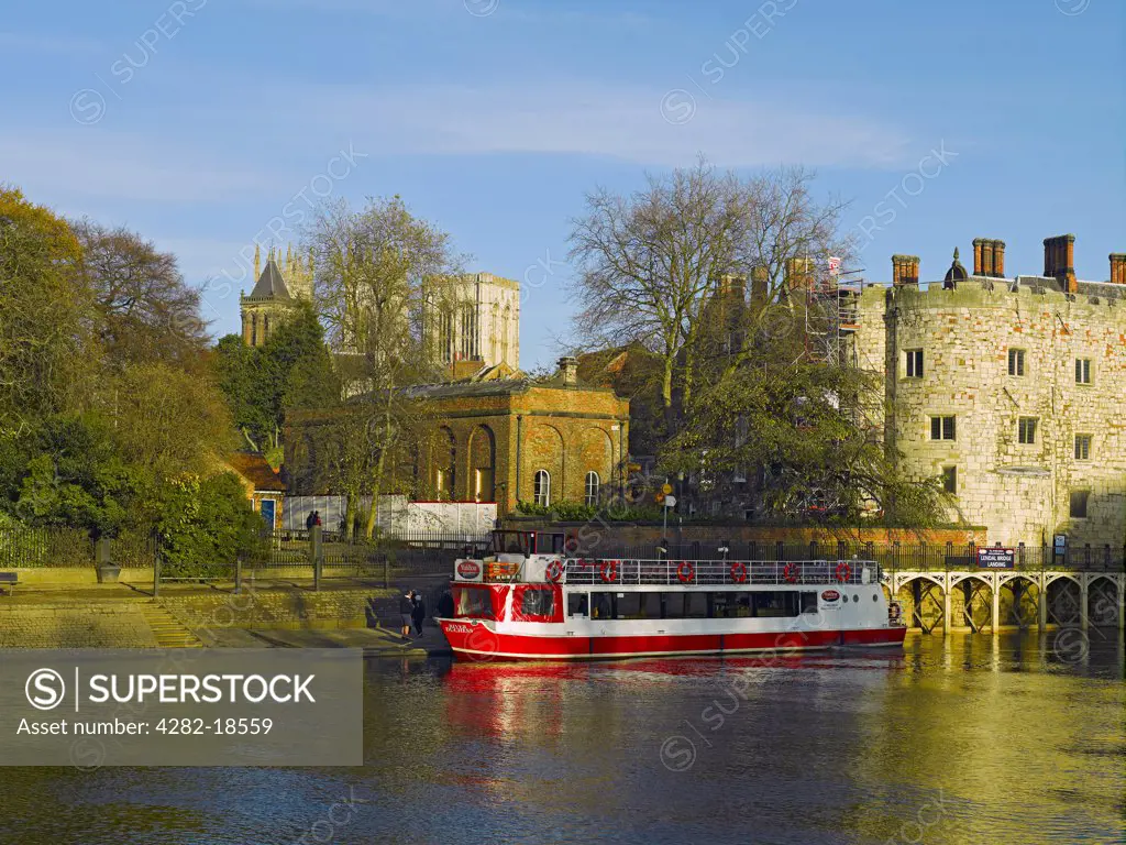 England, North Yorkshire, York. Pleasure boat moored on the River Ouse at Lendal Tower with York Minster in the background.