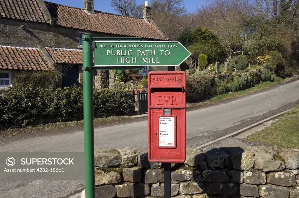 England, North Yorkshire, Low Mill. Old letterbox and North York Moors National Park directional public path sign to High Mill.
