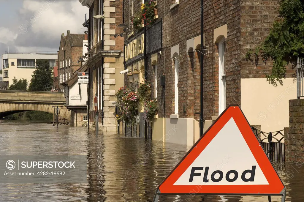 England, North Yorkshire, York. A flood warning sign by the flooded River Ouse in York.
