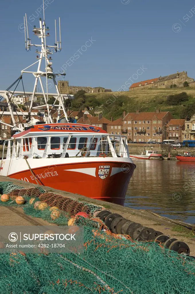 England, North Yorkshire, Whitby. Fishing boats in Whitby Harbour with the church of St Marys in the background.
