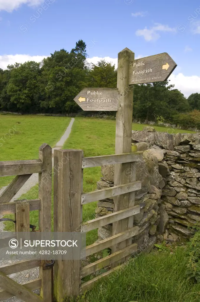England, Cumbria, Hawkshead. Wooden public footpath sign and dry stone wall near to Hawkshead.