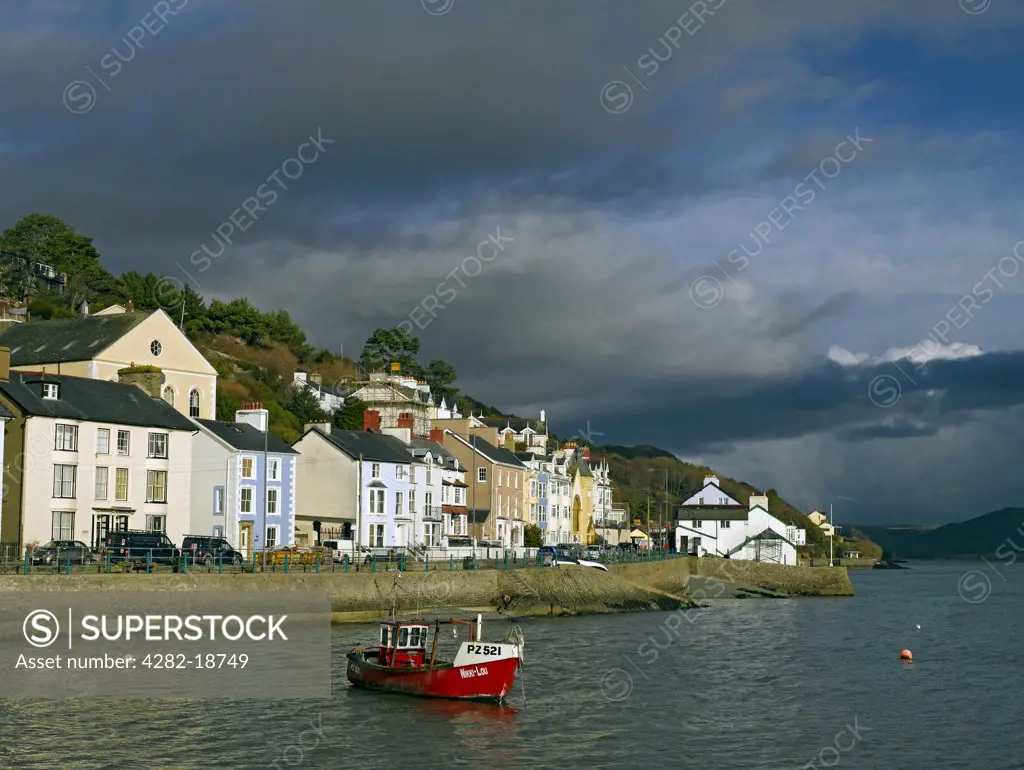 Wales, Gwynedd, Aberdovey. Dark clouds gather over a fishing boat in Aberdovey Harbour within Snowdonia National Park.