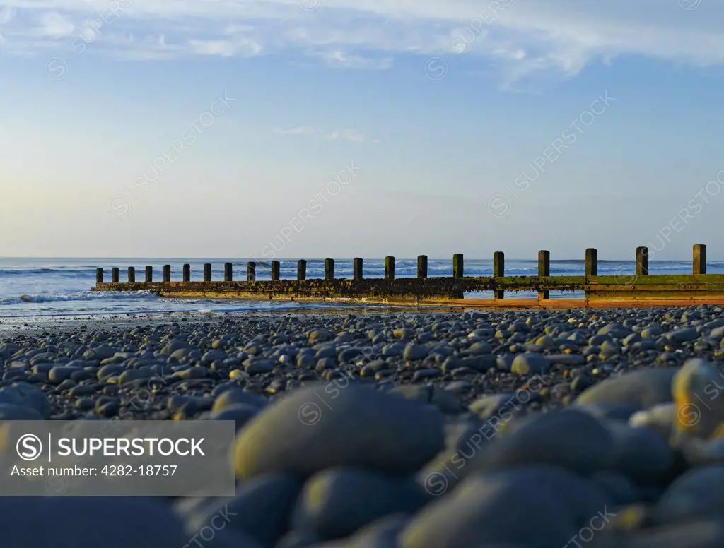Wales, Ceredigion, Borth. Low view over pebbles towards a groyne on the beach at Borth by the Irish Sea.