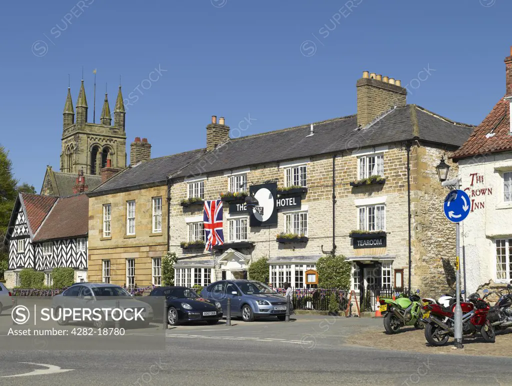 England, North Yorkshire, Helmsley. The Black Swan Hotel, a historic inn now a boutique hotel in Market Place. The tower of All Saints Church is in the background.