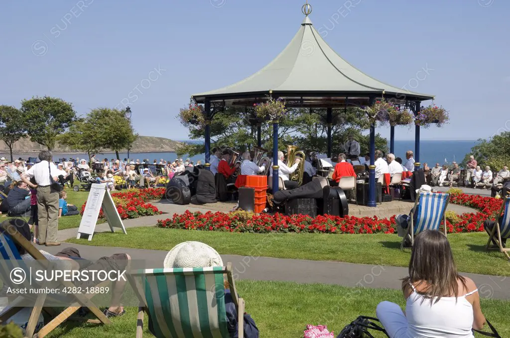 England, North Yorkshire, Filey. Holidaymakers listening to the brass band playing in the bandstand in Crescent Gardens.