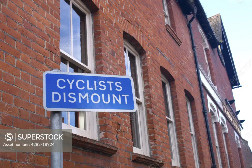 England, Hampshire, Winchester. Cyclists dismount sign in an urban setting. Increasing fuel costs, health benefits and a greater awareness of environmental issues have seen a surge in cycling, especially in major conurbation's.