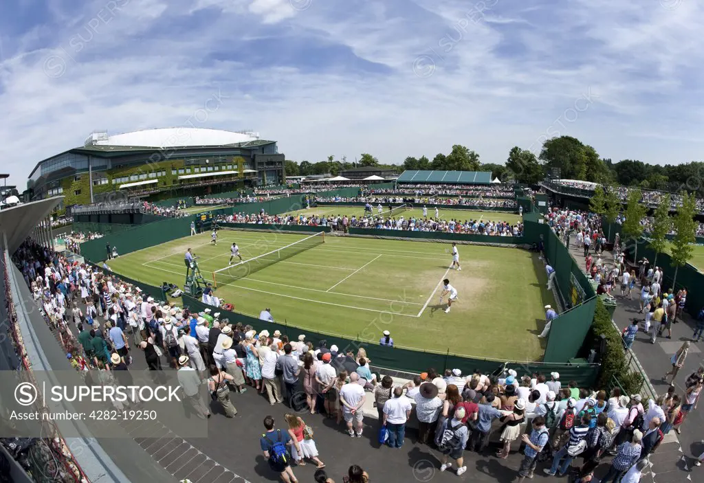 England, London, Wimbledon. A crowd enjoying a mens doubles match on Court no. 8 at the Wimbledon Tennis Championships 2010.