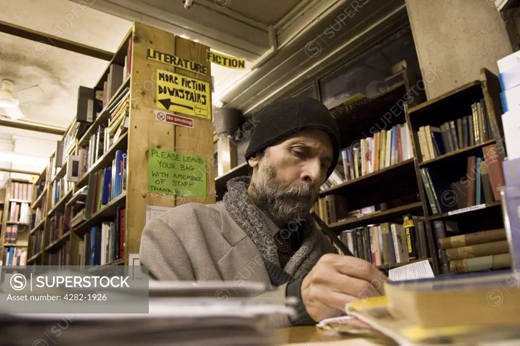 England, London, Charing Cross. Customer in second hand bookshop on Charing Cross Road. Second hand bookshops sell books of varying prices, the most expensive are in Cecil Court where more specialist antiquarian books are found.