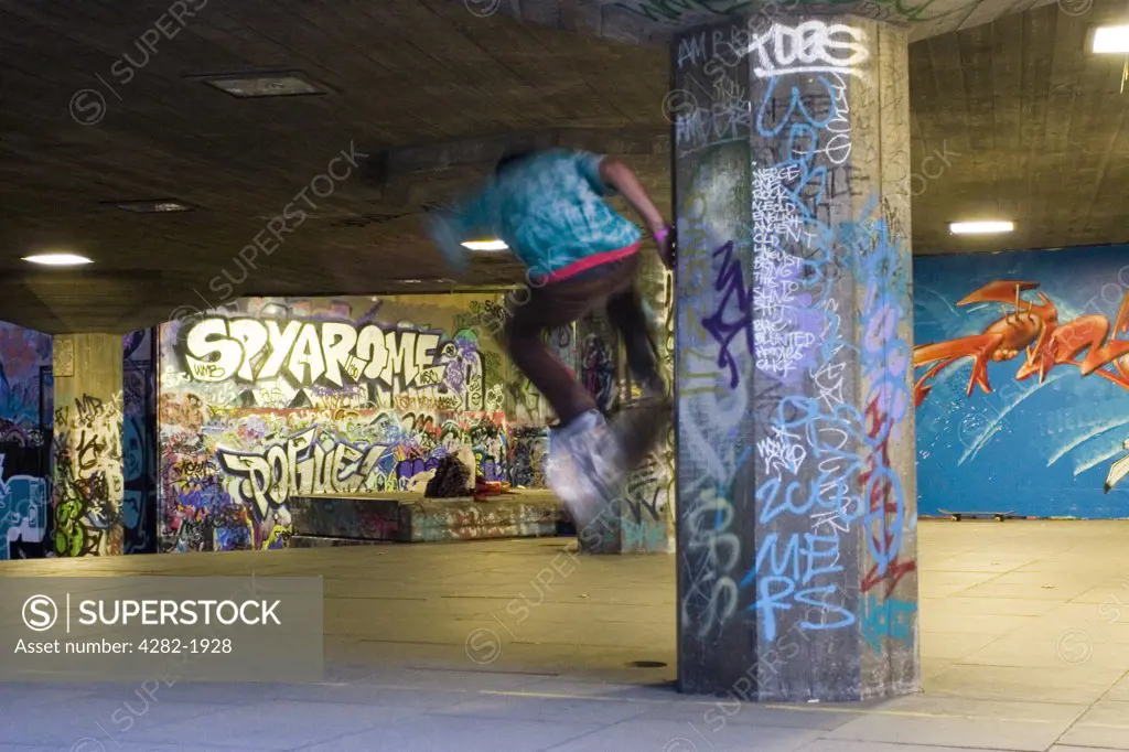 England, London, South Bank. Skateboarder in graffiti'd South Bank. The word 'graffiti' is the plural of 'graffito' and originates from the Italian word 'graffiato' which means scratched.