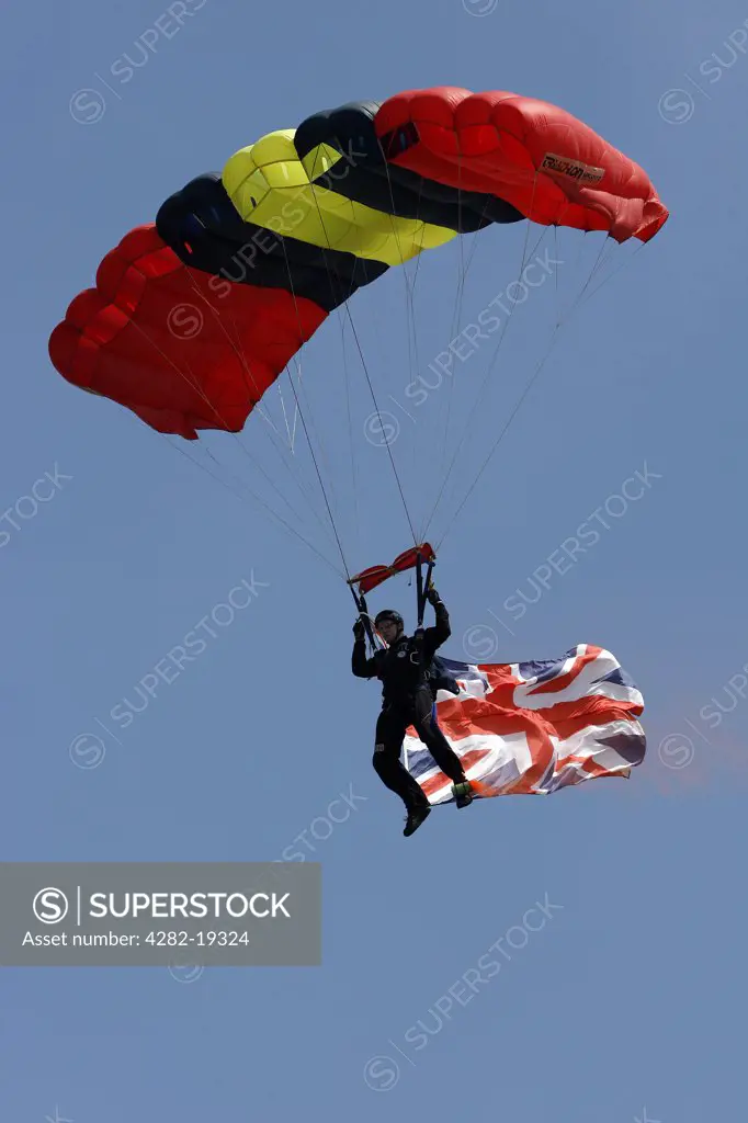 England. A man parachutes to earth carrying the Union flag.