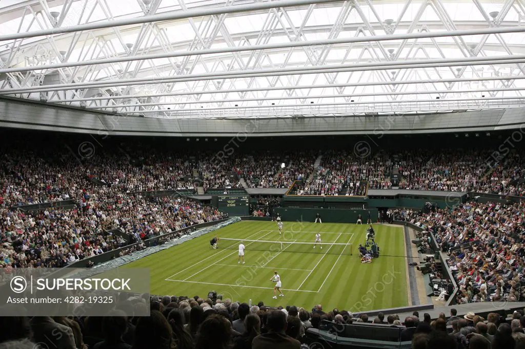 England, London, Wimbledon. A mixed doubles match on Centre Court under the new retractable roof during the Wimbledon Centre Court Celebration event.