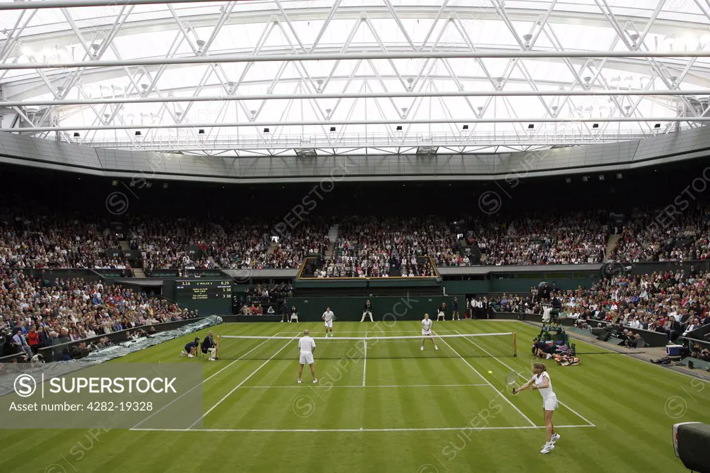England, London, Wimbledon. A mixed doubles match on Centre Court under the new retractable roof during the Wimbledon Centre Court Celebration event.