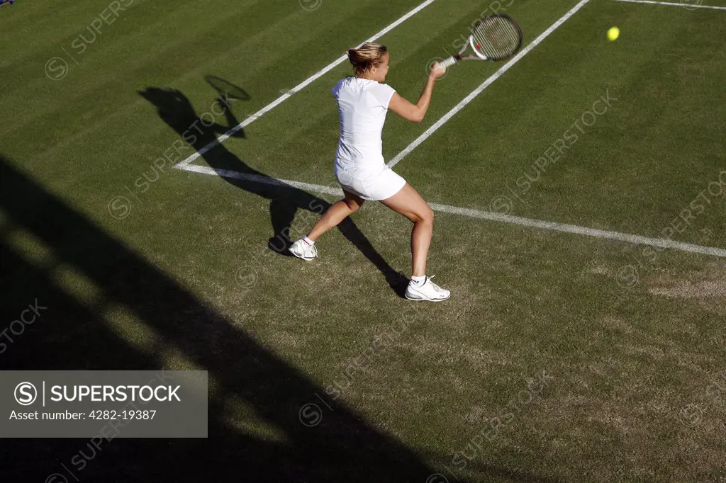 England, London, Wimbledon. A player with shadow hits a return during the Wimbledon Tennis Championships 2008.
