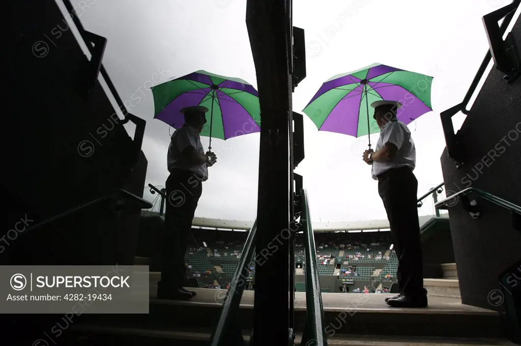 England, London, Wimbledon. A gate steward on court 1 with his umbrella at the Wimbledon Tennis Championships 2008.