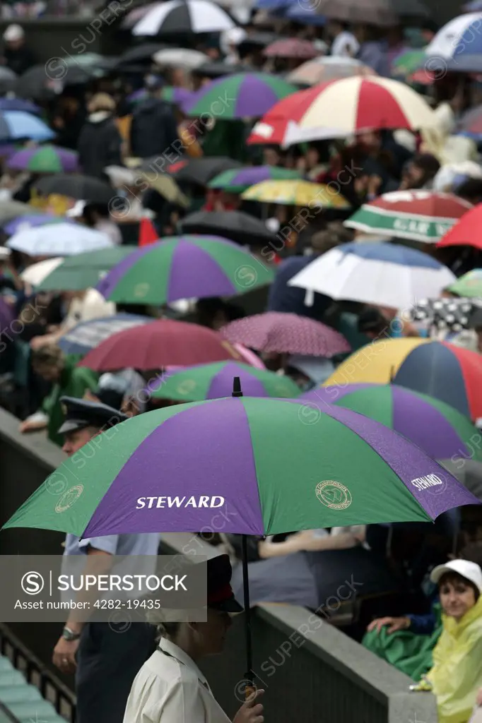 England, London, Wimbledon. Umbrellas go up as the rain starts to fall at the Wimbledon Tennis Championships 2008.