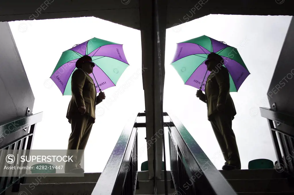England, London, Wimbledon. A Service Steward and his umbrella is reflected in a glass pane in one of the entrances to centre court at the Wimbledon Tennis Championships 2008.