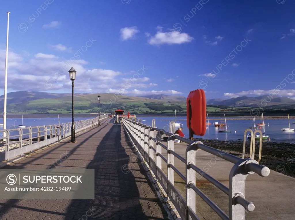 Wales, Anglesey, Beaumaris. View along Beaumaris Pier to the Menai Straits and the mountains of Snowdonia in evening light.
