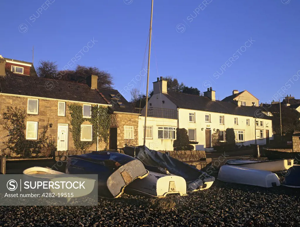 North Wales, Anglesey, Moelfre. Seafront cottages with upturned boats on the shingle beach.