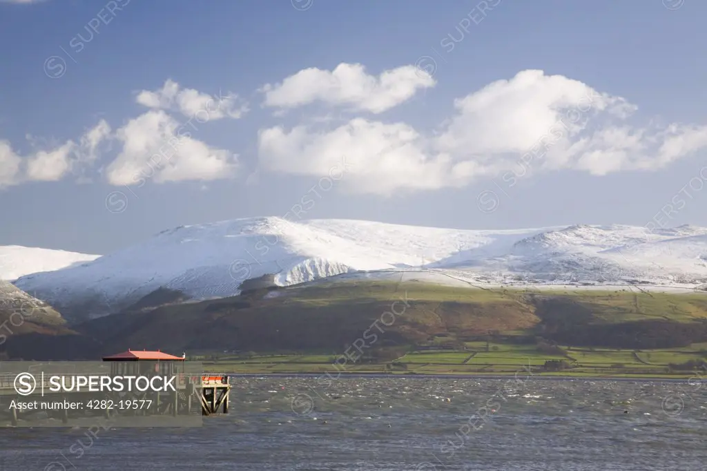 North Wales, Anglesey, Beaumaris. Pier and rough sea with snow covered Carnedd mountain.