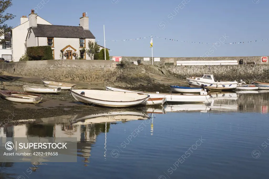 North Wales, Anglesey, Cemaes. Cottage and boats reflected in the calm waters of Cemaes harbour.