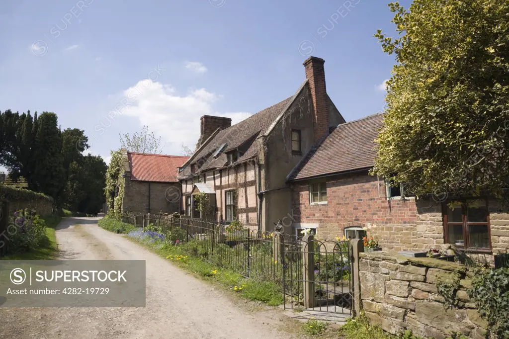 England, Shropshire, Hope Bowdler. A quaint old cottage and outbuildings on a country lane in a rural village.