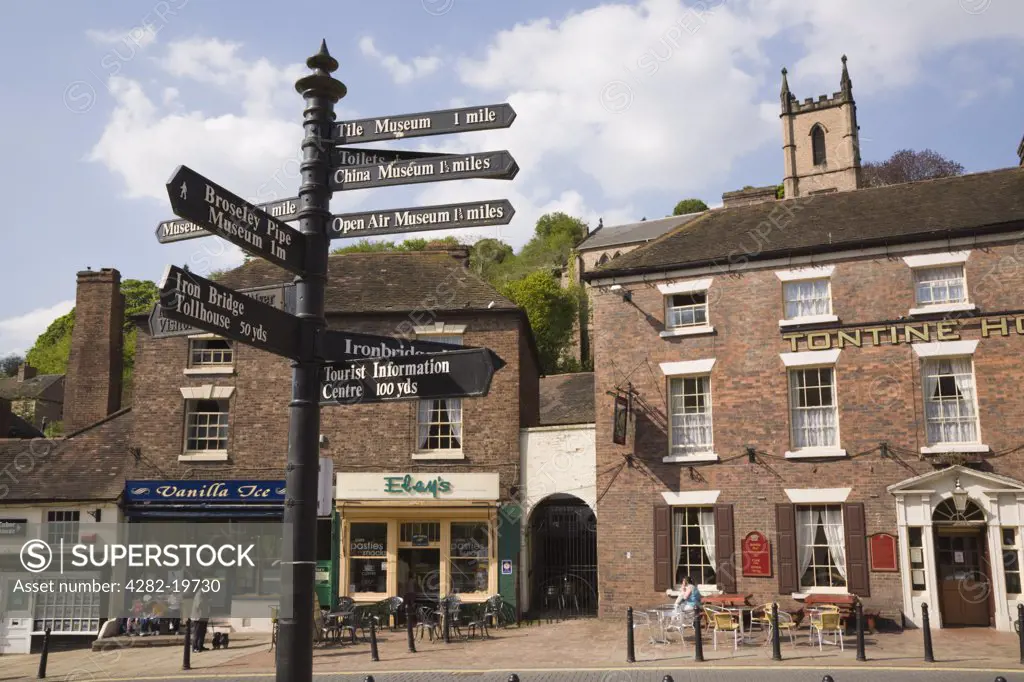 England, Shropshire, Ironbridge. A tourist direction signpost by hotel and shops on Tontine Hill in the town centre.