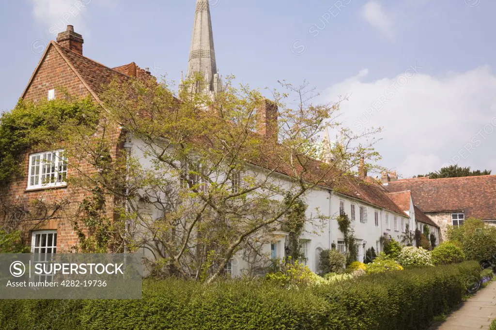 England, West Sussex, Chichester. A row of old cottages with the spire of The Cathedral Church of the Holy Trinity visible behind.