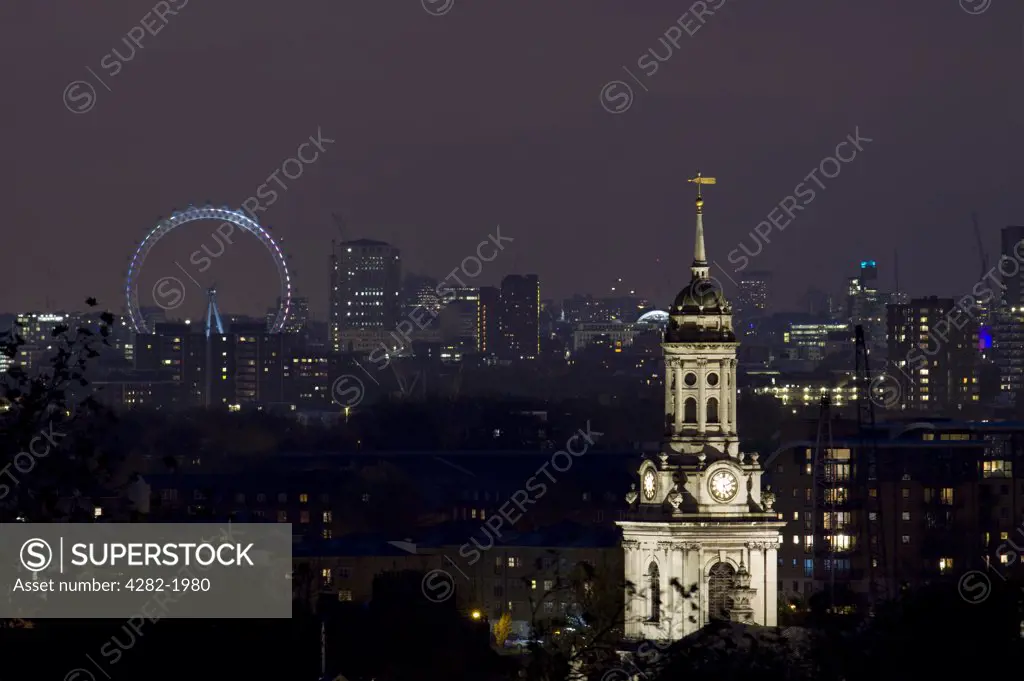 England, London. London skyline at night with a stone clock tower and the London Eye on the horizon.