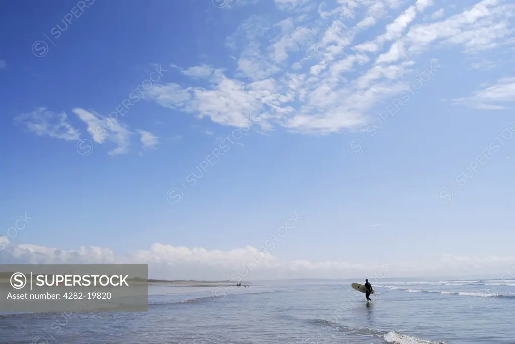 England, North Devon, Saunton Sands. A surfer in the shallows on the beach at Saunton Sands.